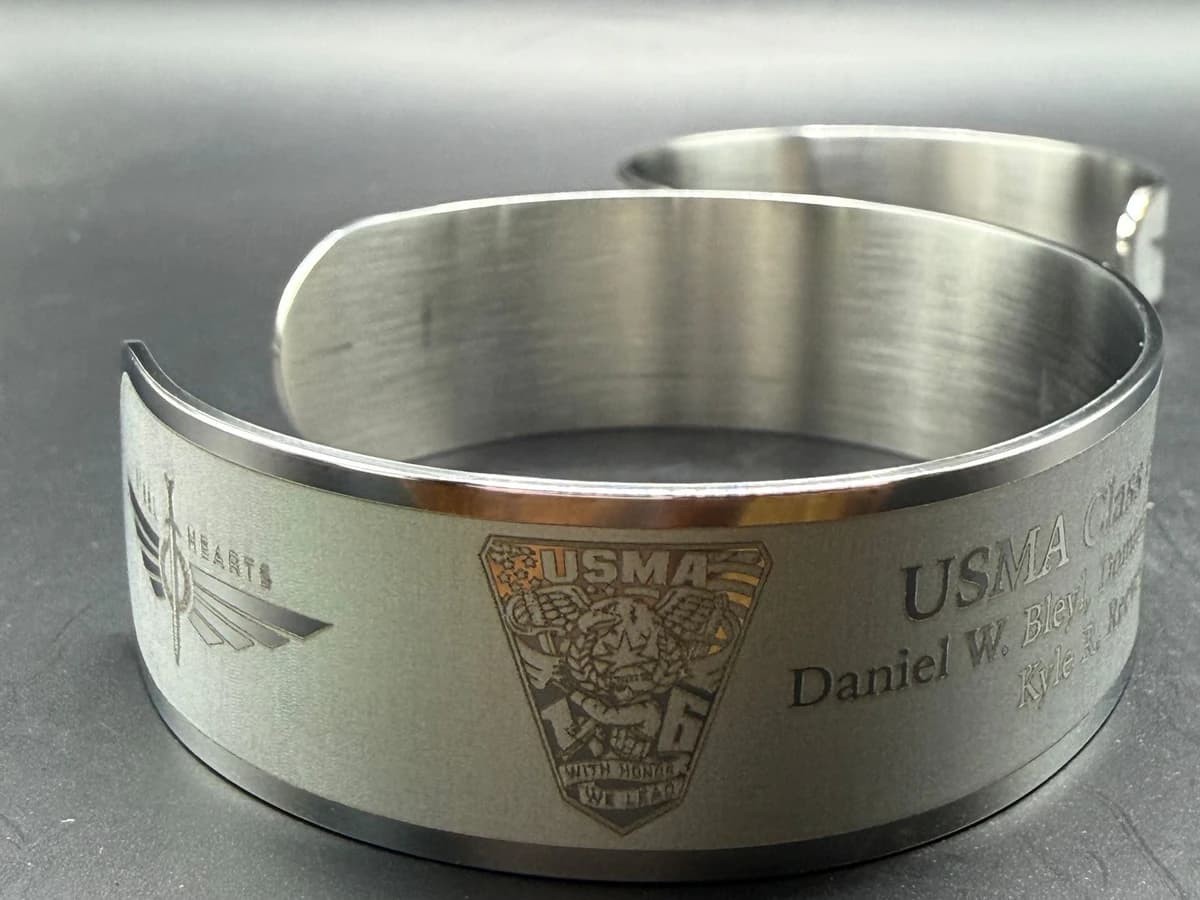 Close view of a USMA Class of 2016 memorial bracelet showing the Steel Hearts mark, class crest, and engraved roster.